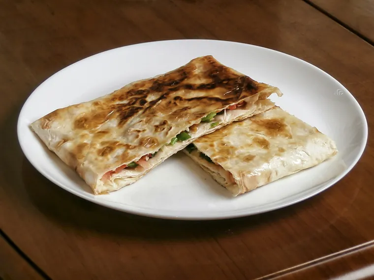 Una piadina farcita e tagliata a metà, nel piatto (immagine illustrativa)